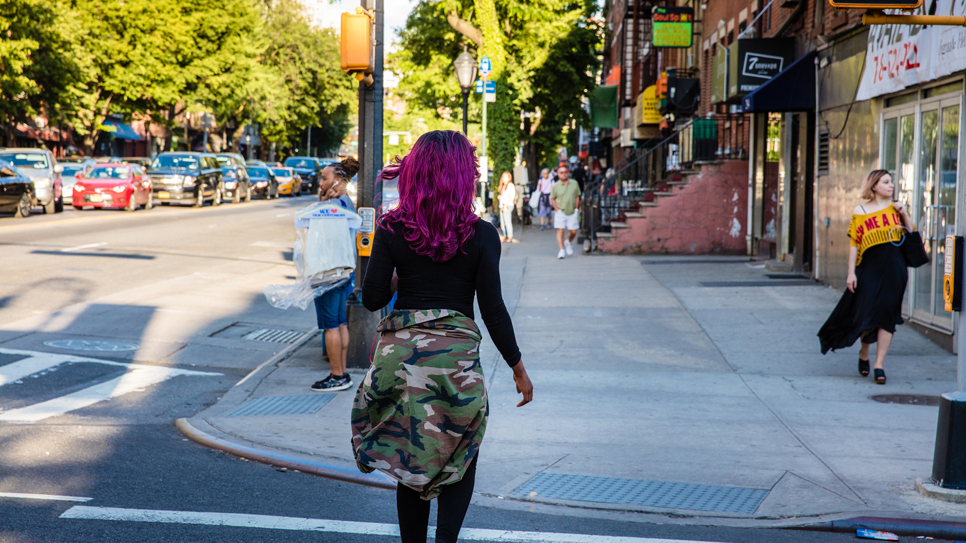 Purple haired woman walking down a busy downtown Brooklyn Street